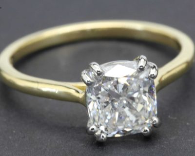 Engagement ring with a large cushion-cut diamond set in a gold band.
