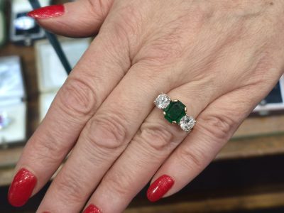 Elegant emerald and diamond ring on a woman's finger, showcasing fine jewelry craftsmanship.