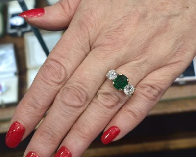 Elegant emerald and diamond ring on a woman's finger, showcasing fine jewelry craftsmanship.