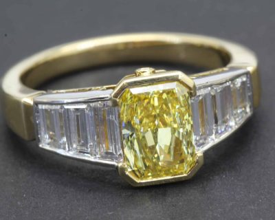 Stunning yellow diamond engagement ring with baguette-cut diamonds in gold setting.