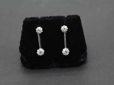Diamond drop earrings with sparkling gemstones on a black velvet display.