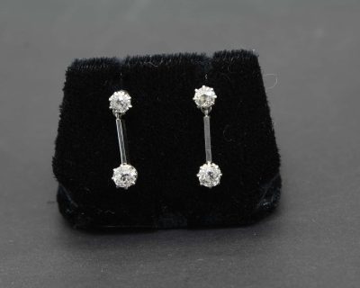 Diamond drop earrings with sparkling gemstones on a black velvet display.