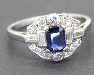Elegant sapphire and diamond ring with a central blue gemstone surrounded by sparkling diamonds.