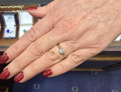 Diamond engagement ring on a woman's hand with red nail polish.