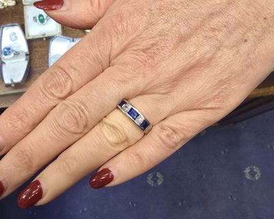 Close-up of a woman's hand wearing a sapphire and silver ring at Weldons Jewellers.