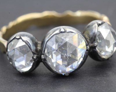 Diamond ring with three large, clear gemstones and a gold band.