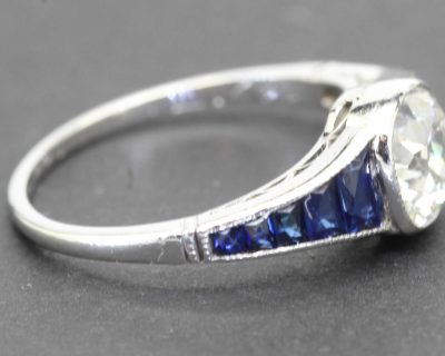Silver engagement ring with a large diamond and blue sapphires, showcasing fine jewelry craftsmanshi.