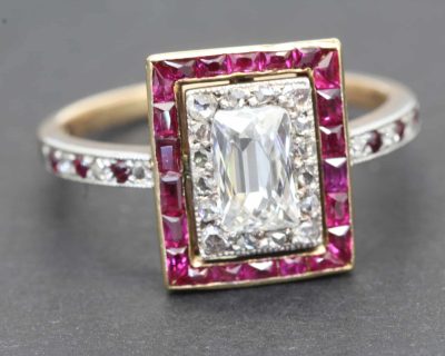 Elegant diamond ring featuring an emerald-cut center stone surrounded by pink gemstones and a diamon.