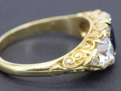 Gold ring with detailed scrollwork and a sparkling central diamond.