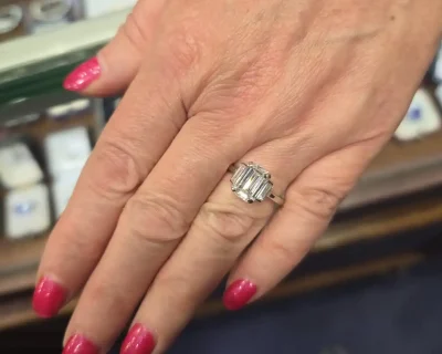 Emerald cut diamond ring on a woman's finger, showcasing fine jewelry craftsmanship.