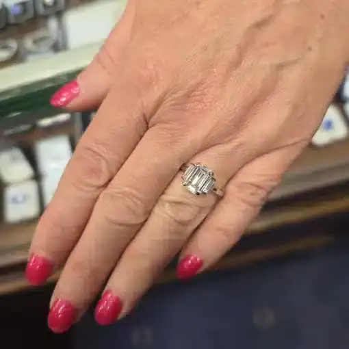 Emerald cut diamond ring on a woman's finger, showcasing fine jewelry craftsmanship.