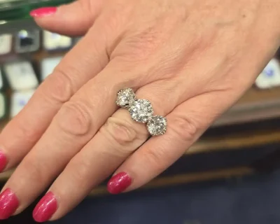 Diamond ring with three sparkling stones on a woman's finger.