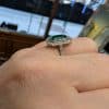 Emerald and diamond ring on hand, side view