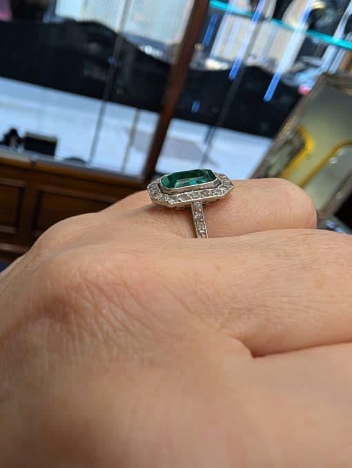 Emerald and diamond ring on hand, side view