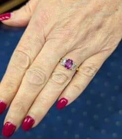 Pink sapphire and diamond three stone ring, view on hand
