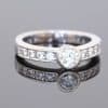Elegant and contemporary in style, this diamond ring combines the clean lines of a bezel setting with the enduring brilliance of diamonds. Its refined design balances the prominence of the central stone with the delicate sparkle of diamond-set shoulders, creating a sophisticated addition to a fine jewellery collection.