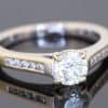 A timeless diamond engagement ring, combining classic design with the added brilliance of diamond-set shoulders. Its elegant proportions and understated white gold setting create a refined jewel designed to be treasured for years to come.