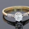 This antique diamond engagement ring combines the romantic appeal of a cushion-cut diamond with the enduring warmth of 18kt gold. Its classic design, enhanced by pavé-set shoulders, offers an elegant balance of character and sparkle.