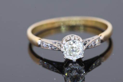 This antique diamond engagement ring combines the romantic appeal of a cushion-cut diamond with the enduring warmth of 18kt gold. Its classic design, enhanced by pavé-set shoulders, offers an elegant balance of character and sparkle.