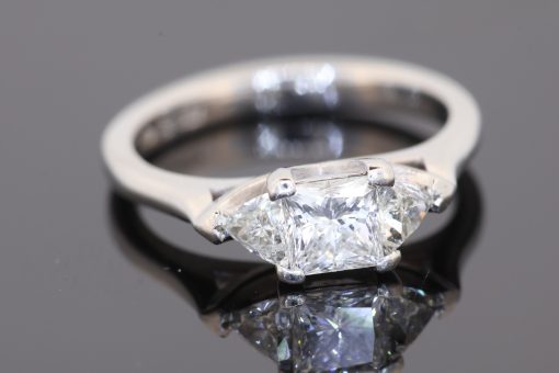 A distinctive three-stone diamond ring that combines geometric elegance with the enduring appeal of platinum. The contrast between a princess-cut centre diamond and trilliant-cut shoulders creates a sophisticated design with crisp lines and a contemporary edge.