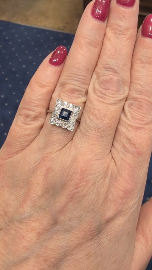 A charming antique sapphire and diamond cluster ring, dating to circa 1923, set in platinum and carrying a wonderfully personal inscription inside the shank: “FHB to Gwen 1923”. The dated dedication gives this elegant jewel a tangible connection to its original owners, transforming it from a beautiful piece of jewellery into a small piece of personal history. The inscription suggests that the ring was presented to Gwen in 1923, making it particularly evocative as a period gift.