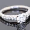 A timeless diamond engagement ring, combining the brilliance of a round brilliant-cut centre diamond with the refined sparkle of diamond-set shoulders. Crafted in 18kt white gold, this elegant design offers a sophisticated expression of enduring commitment.