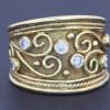 A striking wide gold ring that combines the warmth of precious metal with the brilliance of diamonds and the intricate beauty of applied filigree. Its decorative detailing gives the piece a distinctive character, balancing the bold presence of a broad band with the refinement of traditional goldsmithing.