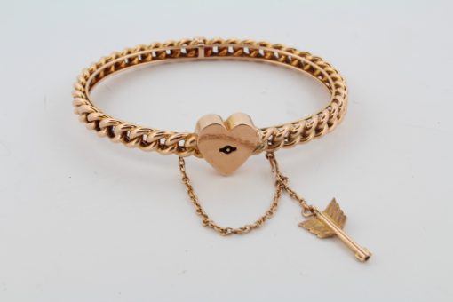 A rare antique 15-karat gold bangle, distinguished by its romantic heart lock and Cupid’s arrow key. Combining symbolic motifs of love and devotion with the enduring appeal of antique gold jewellery, this charming piece offers a glimpse into the sentimental traditions of earlier jewellery design.