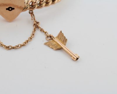 A rare antique 15-karat gold bangle, distinguished by its romantic heart lock and Cupid’s arrow key. Combining symbolic motifs of love and devotion with the enduring appeal of antique gold jewellery, this charming piece offers a glimpse into the sentimental traditions of earlier jewellery design.
