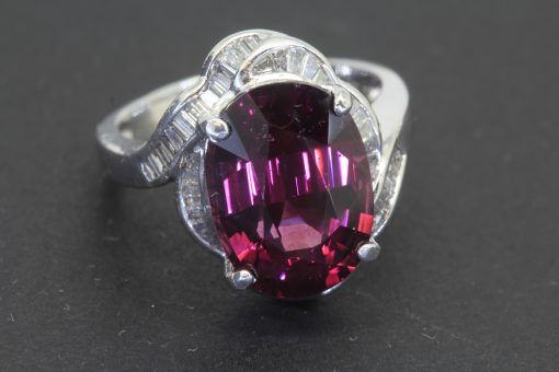 A striking Art Deco ring, combining the bold glamour of the period with an imaginative arrangement of gemstones. Celebrated for its geometric precision and distinctive decorative motifs, Art Deco jewellery often balances strong design with intricate detailing. This ring offers a particularly captivating interpretation, pairing a substantial 9-carat garnet with the refined sparkle of baguette-cut diamonds.