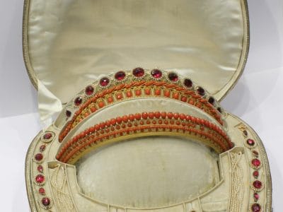 A remarkable antique parure of coral, garnet, cultured pearl, 18kt gold and gilded metal, associated with the Countess du Durat. An extraordinary and highly unusual suite comprising three tiaras, a necklace, a pair of ear pendants, a pair of ear clips and two bracelets. The parure is particularly evocative for its aristocratic association and the extraordinary breadth of the suite. The Comtesses de Durat belonged to a lineage whose history extended through one of the most turbulent periods of French history, navigating the upheavals of the French Revolution before re-establishing their position within aristocratic society during the Napoleonic era. The family also had a Caribbean branch connected with French colonial administration in territories including Grenada and Saint Martin, while members of the family in mainland France maintained important estates and family residences. Among the women associated with the lineage were Jeanne-Caroline de Patouillet de Deservillers and Marie Marguerite Henriette de Durat, figures remembered in regional records for their cultivation and erudition.