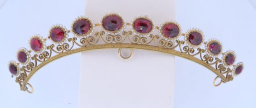 A remarkable antique parure of coral, garnet, cultured pearl, 18kt gold and gilded metal, associated with the Countess du Durat. An extraordinary and highly unusual suite comprising three tiaras, a necklace, a pair of ear pendants, a pair of ear clips and two bracelets. The parure is particularly evocative for its aristocratic association and the extraordinary breadth of the suite. The Comtesses de Durat belonged to a lineage whose history extended through one of the most turbulent periods of French history, navigating the upheavals of the French Revolution before re-establishing their position within aristocratic society during the Napoleonic era. The family also had a Caribbean branch connected with French colonial administration in territories including Grenada and Saint Martin, while members of the family in mainland France maintained important estates and family residences. Among the women associated with the lineage were Jeanne-Caroline de Patouillet de Deservillers and Marie Marguerite Henriette de Durat, figures remembered in regional records for their cultivation and erudition.