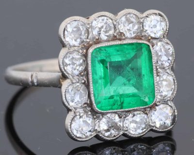 A superb Edwardian emerald and diamond ring, dating to circa 1905 and set in platinum. At its centre is a magnificent 1.5-carat step-cut emerald, distinguished by its exceptional colour and framed by a graceful surround of antique-cut diamonds. The combination of vivid emerald and the cool brilliance of platinum is quintessentially Edwardian, creating a jewel of considerable elegance and character.