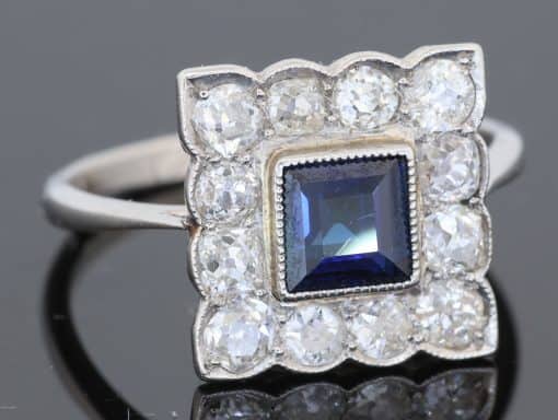 A charming antique sapphire and diamond cluster ring, dating to circa 1923, set in platinum and carrying a wonderfully personal inscription inside the shank: “FHB to Gwen 1923”. The dated dedication gives this elegant jewel a tangible connection to its original owners, transforming it from a beautiful piece of jewellery into a small piece of personal history. The inscription suggests that the ring was presented to Gwen in 1923, making it particularly evocative as a period gift.