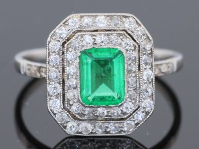 A beautiful Belle Époque emerald and diamond cluster ring, made in France circa 1910 and showcasing the period’s love of delicate platinum construction, fine diamonds and richly coloured gemstones. At its centre is a superb 1-carat Colombian emerald, surrounded by a double halo of diamonds that enhances the stone’s natural colour and gives the ring an elegant, balanced appearance.