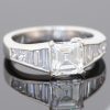 A superb diamond ring distinguished by the striking geometry of a rare carré-cut diamond. Celebrated for its clean lines and architectural elegance, the carré cut brings a distinctive character to this exceptional design, beautifully complemented by the precision and sparkle of its accompanying diamonds.