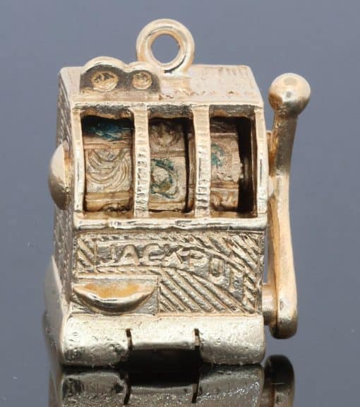 A wonderfully whimsical gold novelty charm in the form of a one-armed bandit, capturing the playful spirit of traditional gambling machines in miniature. The charm is particularly appealing for its working mechanism, transforming an instantly recognisable slot machine into an ingenious piece of novelty jewellery.
