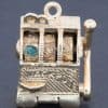 A wonderfully whimsical gold novelty charm in the form of a one-armed bandit, capturing the playful spirit of traditional gambling machines in miniature. The charm is particularly appealing for its working mechanism, transforming an instantly recognisable slot machine into an ingenious piece of novelty jewellery.