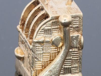 A wonderfully whimsical gold novelty charm in the form of a one-armed bandit, capturing the playful spirit of traditional gambling machines in miniature. The charm is particularly appealing for its working mechanism, transforming an instantly recognisable slot machine into an ingenious piece of novelty jewellery.