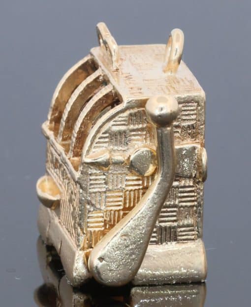 A wonderfully whimsical gold novelty charm in the form of a one-armed bandit, capturing the playful spirit of traditional gambling machines in miniature. The charm is particularly appealing for its working mechanism, transforming an instantly recognisable slot machine into an ingenious piece of novelty jewellery.