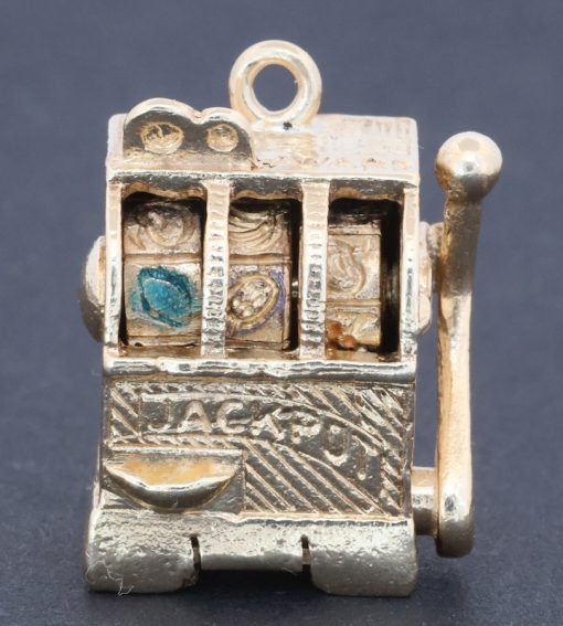 A wonderfully whimsical gold novelty charm in the form of a one-armed bandit, capturing the playful spirit of traditional gambling machines in miniature. The charm is particularly appealing for its working mechanism, transforming an instantly recognisable slot machine into an ingenious piece of novelty jewellery.