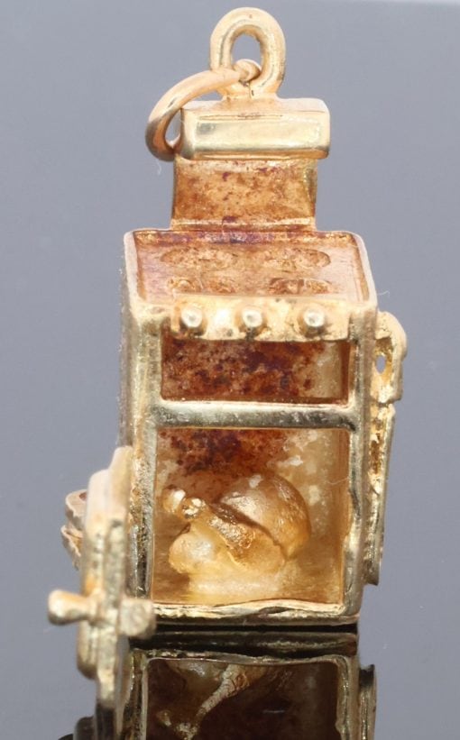 A wonderfully rare 9kt gold novelty charm in the form of a traditional cooker, complete with a charming surprise inside. The piece is a delightful example of the whimsical and imaginative approach taken to novelty jewellery, transforming an everyday household object into a miniature gold charm.