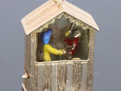 An extremely rare and wonderfully whimsical large gold charm depicting a Punch & Judy show, capturing the theatrical character and humour of one of Britain’s most enduring forms of popular entertainment. Punch & Judy performances have long been associated with seaside resorts, fairs and street entertainment, making this an especially charming subject for a piece of jewellery. The remarkable mechanical element makes the charm particularly unusual and collectible.