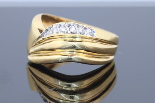 Distinctive and elegant, this wide diamond ring combines the warm lustre of gold with the brilliance of diamonds in an expressive, flowing design. Its unusual wave pattern gives the ring a sculptural quality, creating a piece that balances bold proportions with refined detailing.